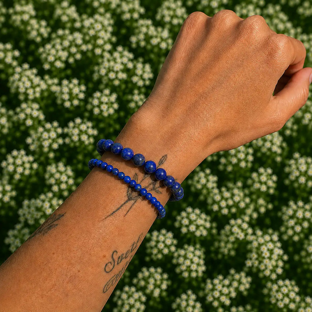 Pulsera lapislázuli en la muñeca, elaborada con piedras azules y motas doradas, destacando su belleza natural.
